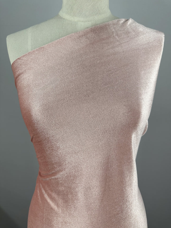 A mannequin elegantly displays the Stretch Velour Peachskin fabric from Super Cheap Fabrics, gracefully draping over one shoulder against a gray background.