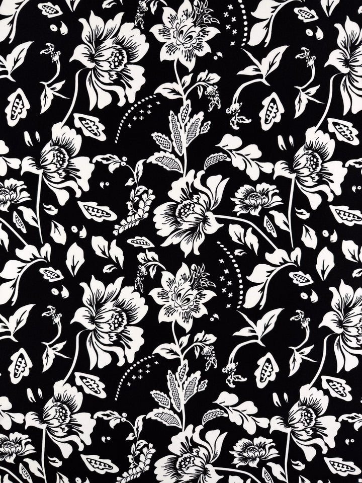 Super Cheap Fabrics’ Printed Lycra - Monochrome Botanica - 150cm features a black and white floral print with large flowers and buds on medium weight lycra, offering comfort and versatility in a symmetrical repeating design.
