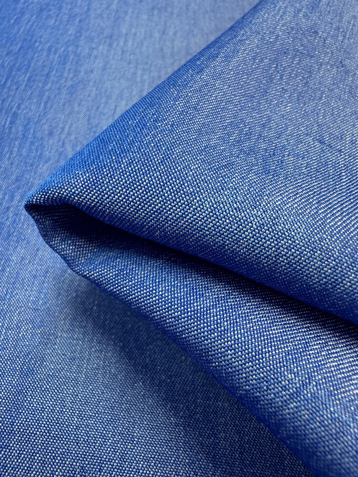 Close-up of the folded Chambray - Victoria Blue - 150cm from Super Cheap Fabrics, highlighting the texture and weave pattern. This lightweight material has a slight sheen that emphasizes its smooth finish and vibrant color.