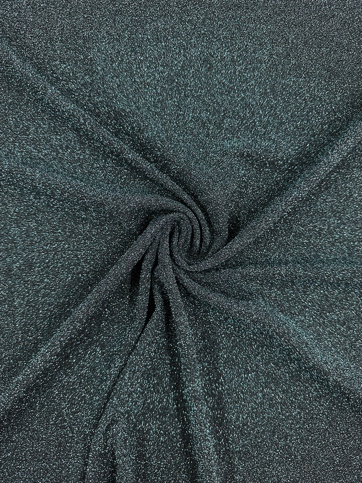 A detailed view of the sparkly, textured Metallic Lycra in Aqua Fuzz by Super Cheap Fabrics, showcasing a spiral fold at the center that forms a swirl pattern, reminiscent of elegant dresses.