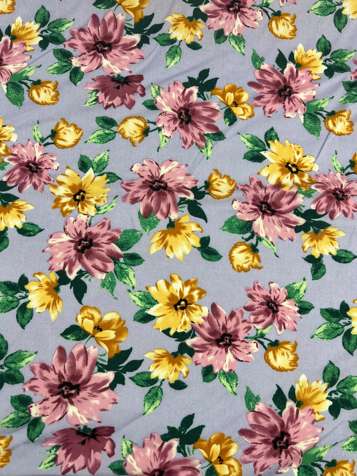 Introducing the Printed Rayon - Watercolour 2.0 from Super Cheap Fabrics, a high-quality fabric featuring a floral pattern with pink and yellow flowers and green leaves against a light gray background. The flowers come in varying sizes and are evenly distributed, creating a vibrant and colorful design that makes this 145cm wide fabric an excellent choice for all sorts of projects.