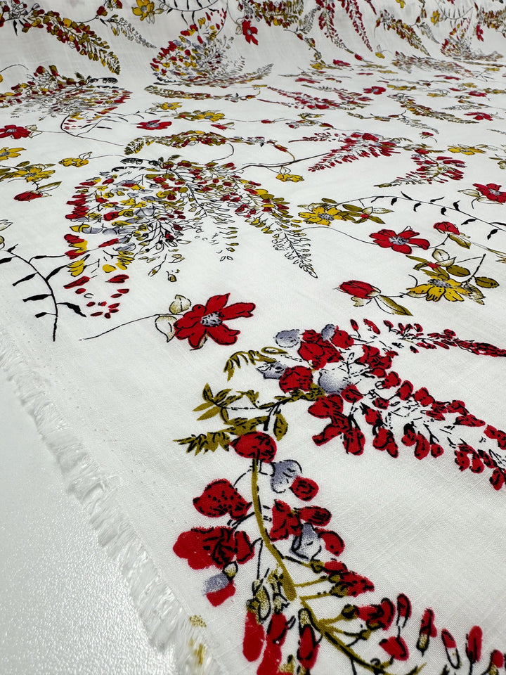 The Scarlet Vine Linen Blend from Super Cheap Fabrics is a lightweight, 145cm-wide textile with a vibrant red, yellow, and green botanical print featuring intricate floral and foliage patterns. Ideal for summer outfits, the material has slightly frayed edges.