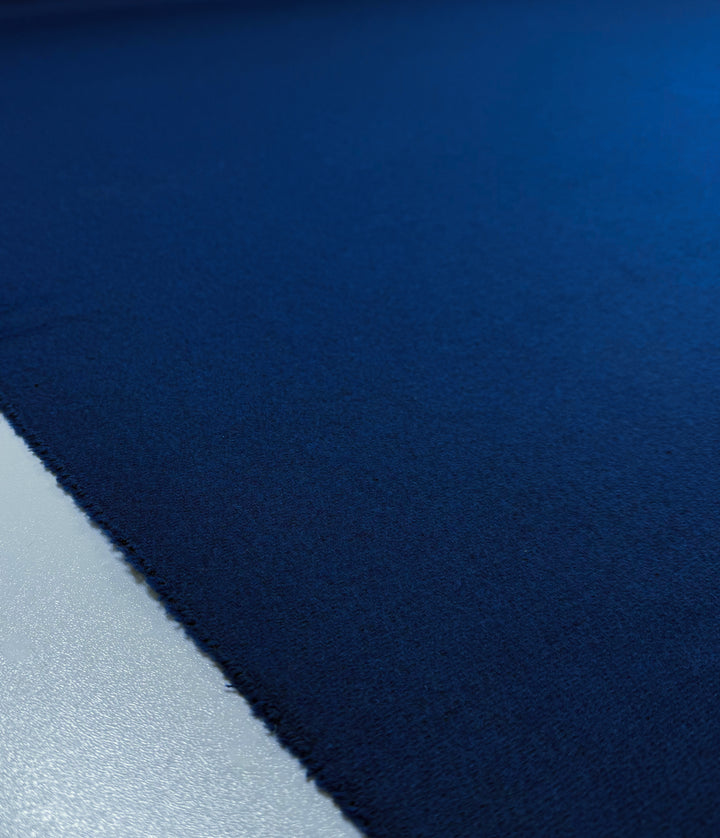 A close-up of Super Cheap Fabrics’ Melton Wool - Blue Quartz - 150cm, showing its rich blue color and heavy weight with a slightly frayed edge on a light background.