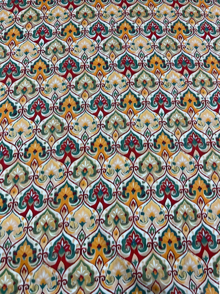 The Designer Rayon - Belle - 145cm from Super Cheap Fabrics showcases a vibrant and detailed geometric pattern with interlocking shapes in shades of green, red, yellow, and white. This ornate yet symmetrical design on rayon fabric is perfect for those who enjoy prints inspired by classic textile motifs.