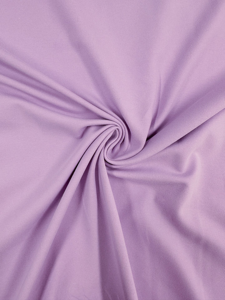 Close-up of "Cotton Lycra - Orchid Bouquet - 170cm" by Super Cheap Fabrics, showcasing a spiral fold pattern in lilac. The medium weight fabric appears soft and smooth, with a swirling effect reminiscent of an orchid bouquet.