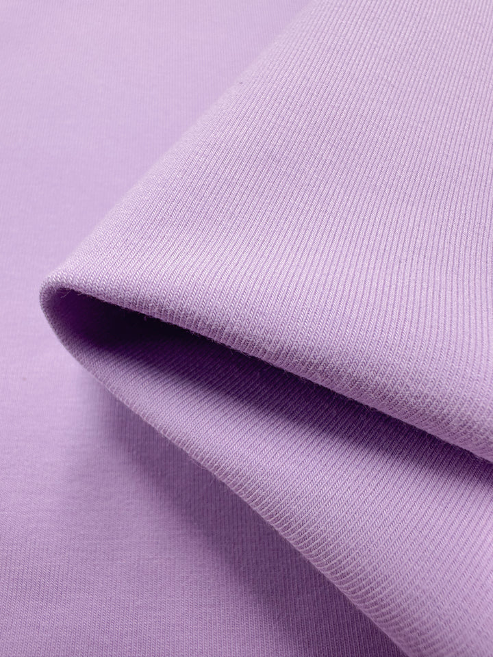 Close-up of the Cotton Lycra - Orchid Bouquet - 170cm by Super Cheap Fabrics, highlighting its ribbed texture and smooth light purple surface with a folded edge.