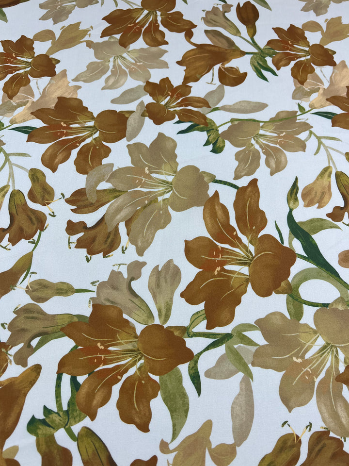 The Designer Rayon - Autumn Gold from Super Cheap Fabrics showcases a floral pattern with brown and green leaves and flowers set against a white background. This Rayon fabric offers a versatile, repetitive motif that delivers an earthy and organic appearance. The fabric is 145cm wide.