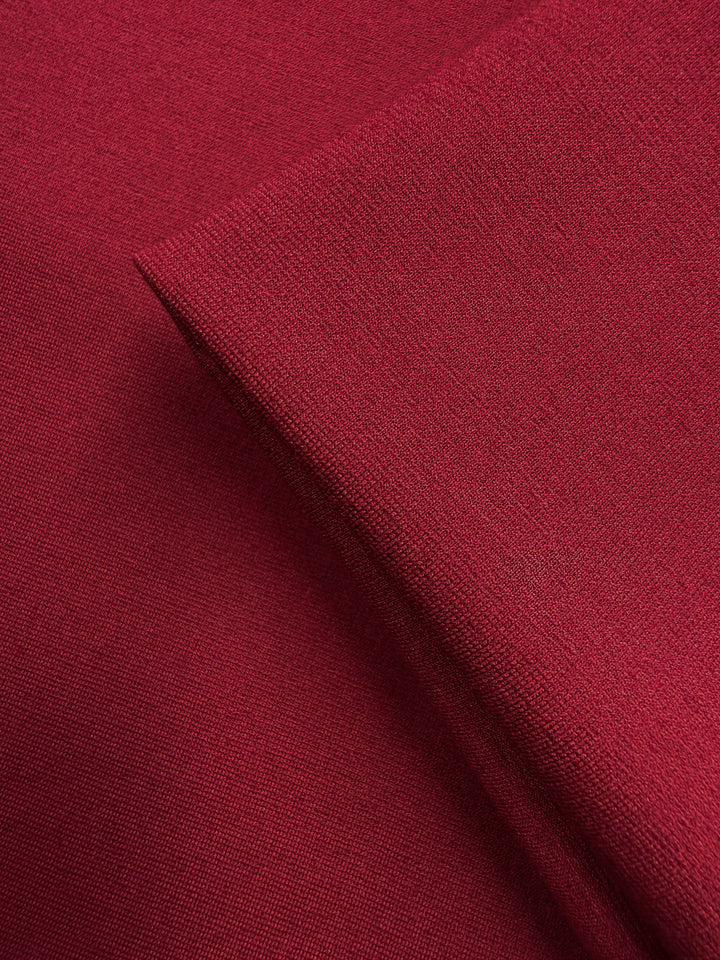 Close-up of two layers of Super Cheap Fabrics' Milano Ponte - Cabernet (160cm), highlighting the fabric's smooth texture, fine weave, and subtle stretch in a rich dark red shade.