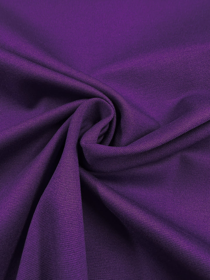 A close-up of Milano Ponte - Violet Indigo by Super Cheap Fabrics shows smooth, heavyweight fabric with a visible swirl and soft folds, highlighting its texture and drape—ideal for stretch suiting and fitted dresses. Width: 165cm.