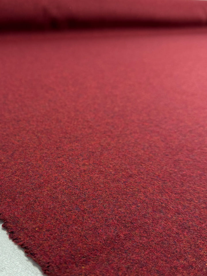 A close-up of Super Cheap Fabrics’ Wool Cashmere in Syrah Marle (152cm), showing the rich red, softly textured luxury fabric spread flat with a frayed edge in the foreground.