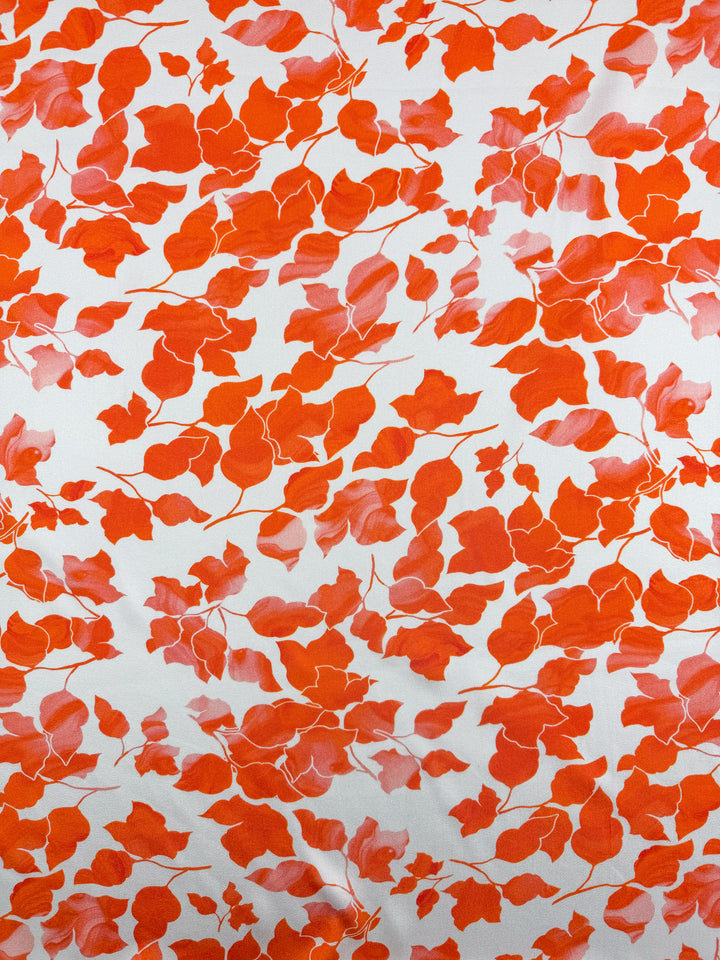 Super Cheap Fabrics' Mercerised Rayon - Flameleaf - 150cm is a white, breathable fabric with an all-over print of orange and red leafy branches in varied sizes, creating a lively, organic pattern.