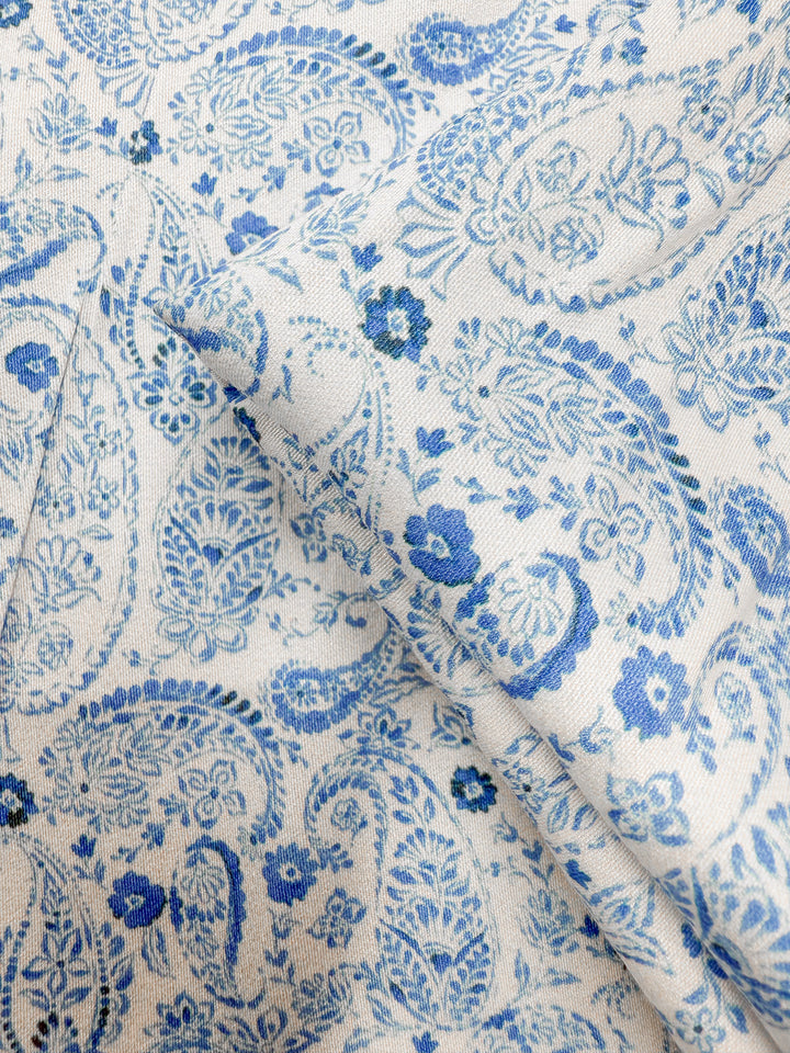 Close-up of Mercerised Rayon - Delft Vine (150cm) by Super Cheap Fabrics, featuring intricate blue paisley and floral patterns on lightweight, silky soft fabric with a smooth texture and detailed designs.
