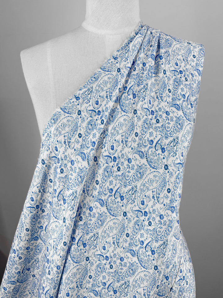 A mannequin displays Super Cheap Fabrics’ Mercerised Rayon - Delft Vine (150cm), a lightweight rayon with a blue paisley and floral design, set against a plain gray background.