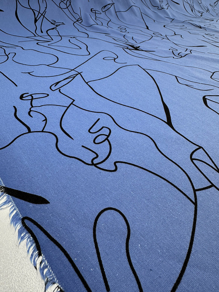 A close-up of Super Cheap Fabrics' Linen Blend - Blue Yonder (147cm) showcases its lightweight texture in a Blue Yonder shade. It features abstract black line art and draped fabric with a fringed edge, ideal for artistic home decor.