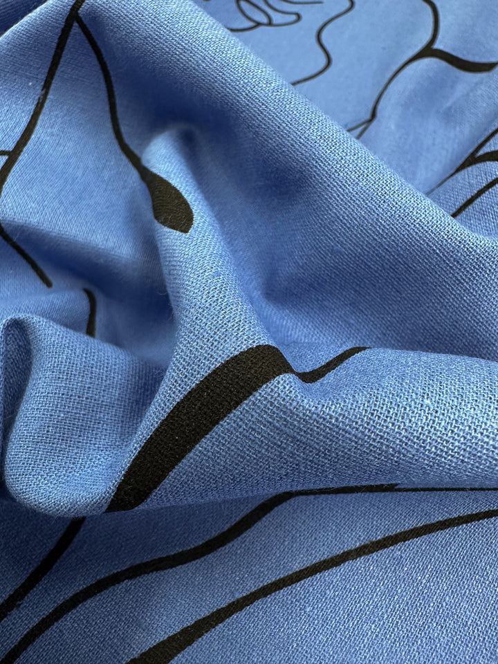 Close-up of Super Cheap Fabrics' Linen Blend - Blue Yonder, showcasing black abstract lines and textured wrinkles. This lightweight fabric, ideal for home decor, adds artistic flair to any room with its 147cm width.