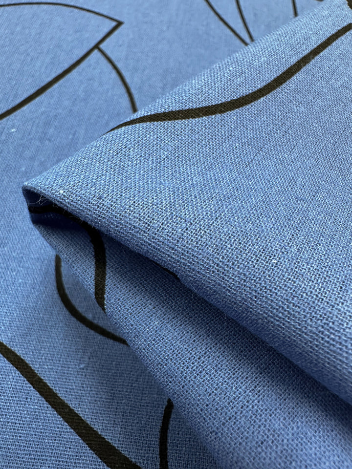 Close-up of folded Linen Blend - Blue Yonder fabric by Super Cheap Fabrics, featuring a subtle black outline floral print. The fine weave highlights its smooth and soft texture, making it ideal for home decor in lightweight linen styles. Width: 147cm.