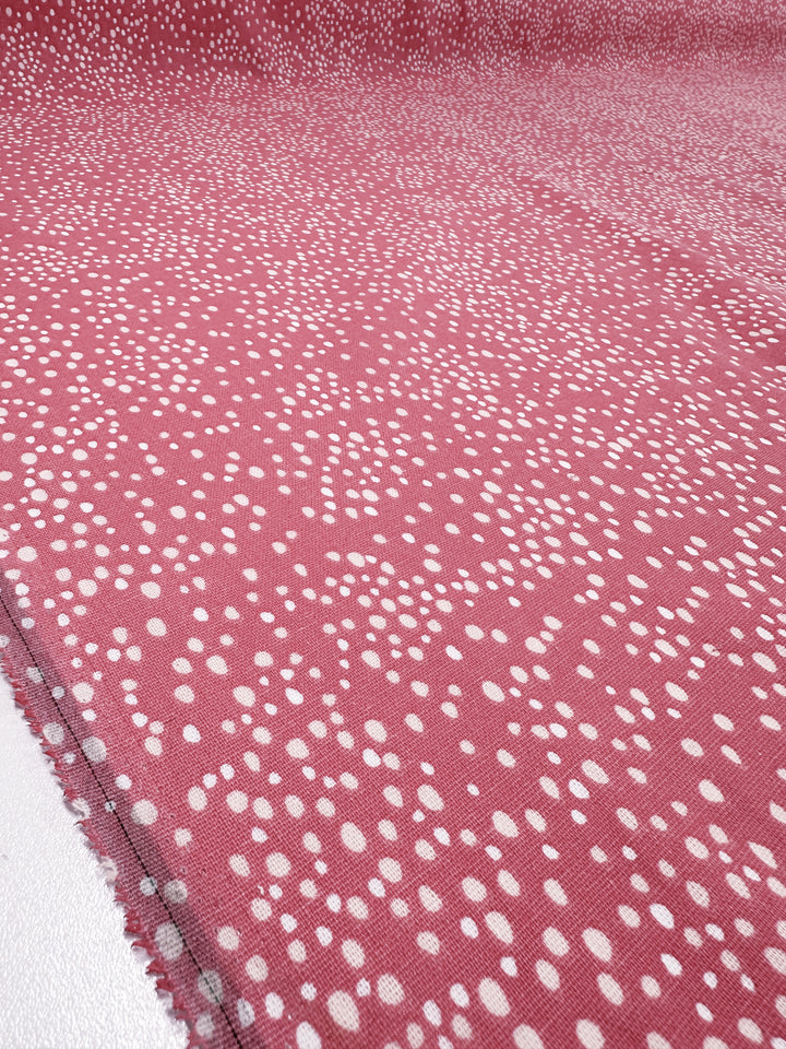 Close-up of Super Cheap Fabrics' Linen Blend - Spotty - 140cm, featuring a pink base with scattered white dots, laid flat to highlight its textured charm for home decor.