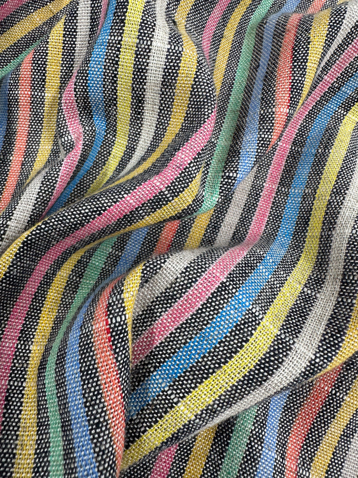 The Linen Blend - Beachside by Super Cheap Fabrics, measuring 143cm wide, features a close-up of woven medium-weight linen with colorful wavy stripes in black, white, pink, yellow, green, and blue. These intersecting stripes form a dynamic vintage pattern on its textured surface.