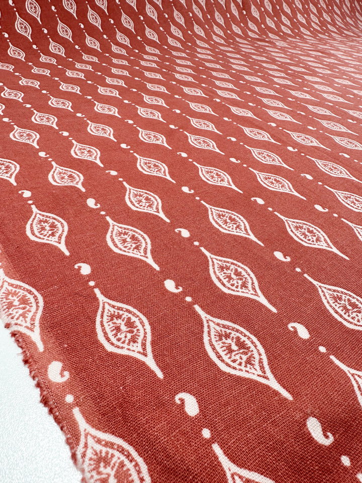 The 130cm Linen Blend - Repeater by Super Cheap Fabrics features a red linen with evenly spaced white paisley motifs, enhancing the texture and making it perfect for creating stylish children's clothing.