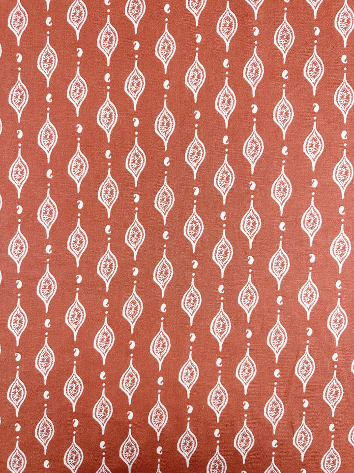 The Linen Blend - Repeater from Super Cheap Fabrics features detailed white paisley patterns in vertical rows on an apricot brandy brown backdrop, ideal for creating elegant children's clothing.