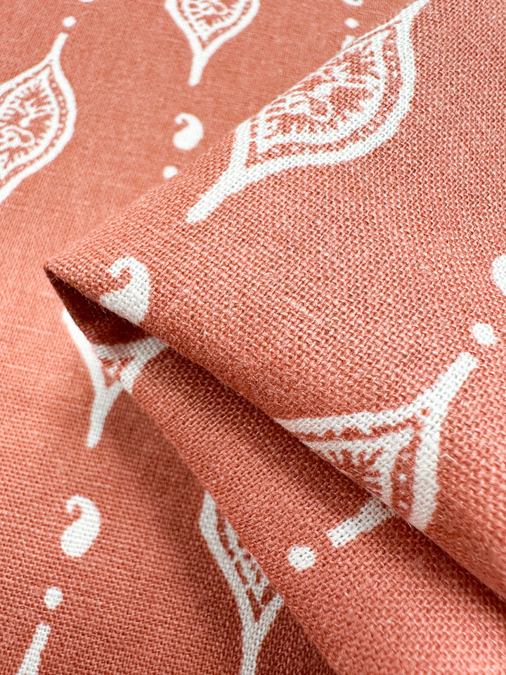 A close-up of Super Cheap Fabrics' Linen Blend - Repeater fabric, featuring a pink background with white leaf-like patterns and a woven texture that offers a soft, durable feel. Perfect for charming children's clothing designs. Width: 130cm.