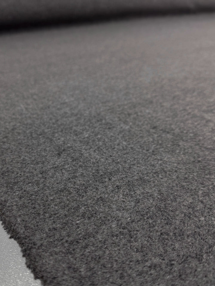 A close-up of Super Cheap Fabrics’ Melton Wool - Charcoal - 150cm, featuring a soft, fuzzy dark gray surface with textured detail fading into the background.