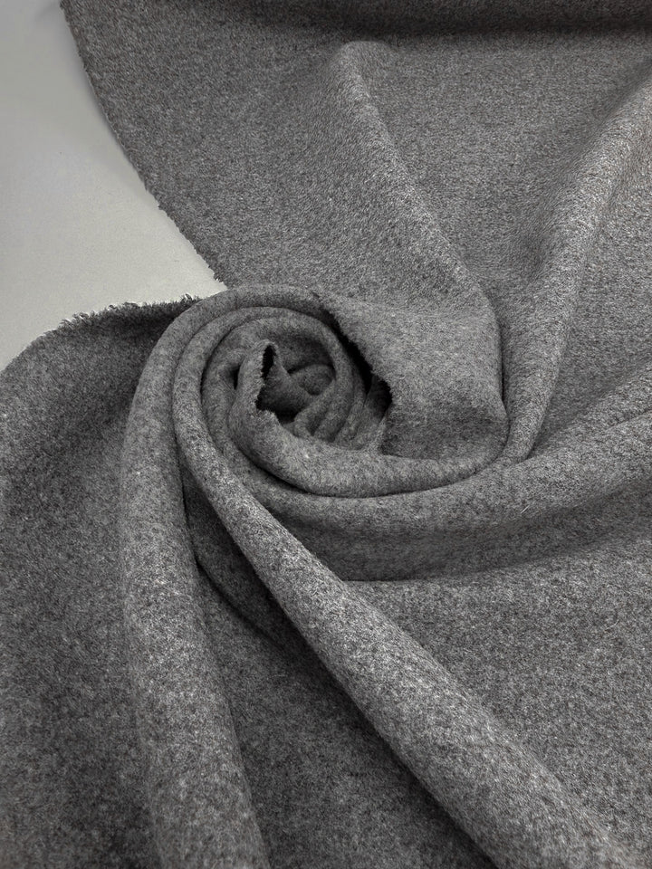 A close-up of Super Cheap Fabrics' Melton Wool - Charcoal - 150cm displays its thick, textured surface in a swirl, highlighting the cozy, premium quality—perfect for outerwear.