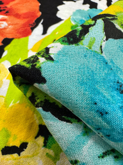 Close-up of the Linen Blend - Black Forest by Super Cheap Fabrics, showcasing vibrant floral patterns in bold red, yellow, blue, and green hues. The 145cm wide fabric is perfect for diverse home decor uses, with its stunning texture visible in the image.