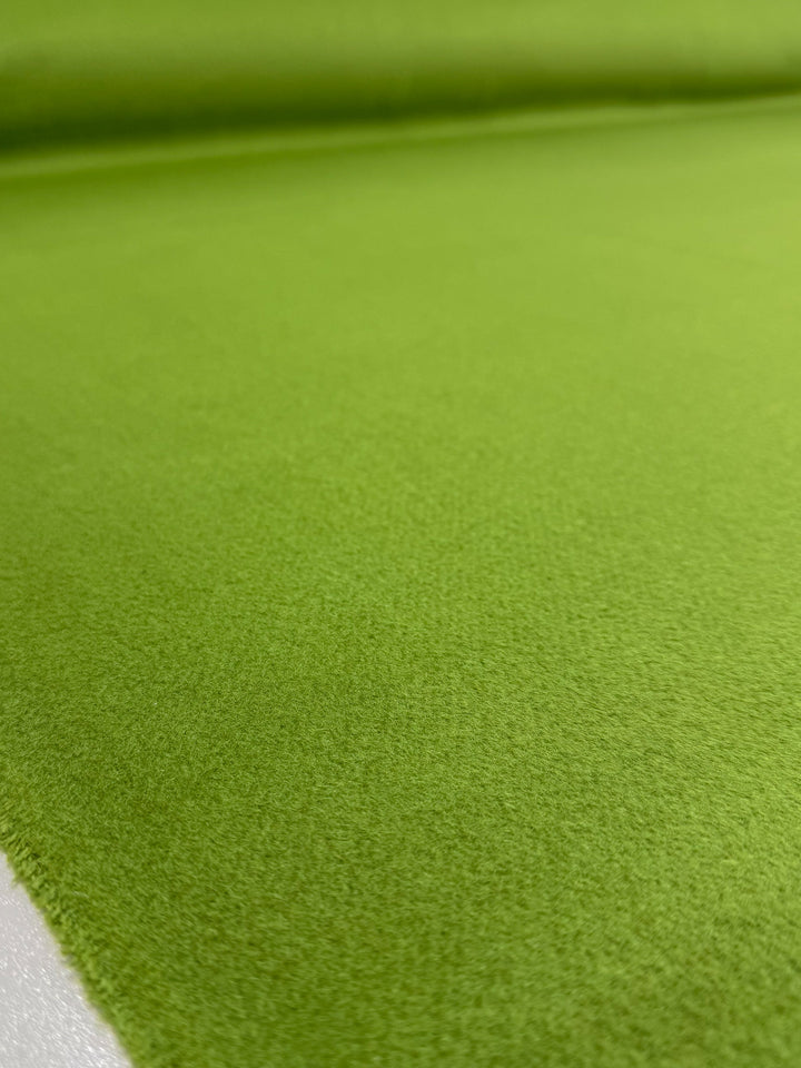 A close-up of Super Cheap Fabrics' Wool Cashmere - Titanite (154cm), featuring its smooth, bright green surface, soft texture, and even color. The fabric is laid flat, filling the whole frame.