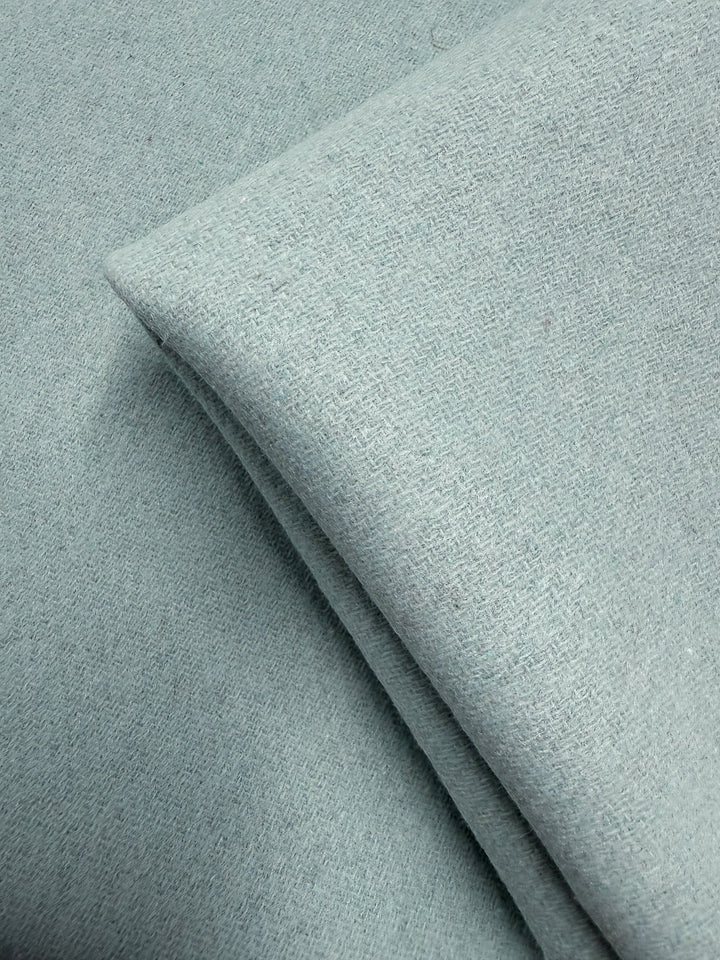 A close-up of Wool Cashmere - Blue Glass - 150cm from Super Cheap Fabrics shows its light blue hue, subtle textured weave, and luxurious softness.