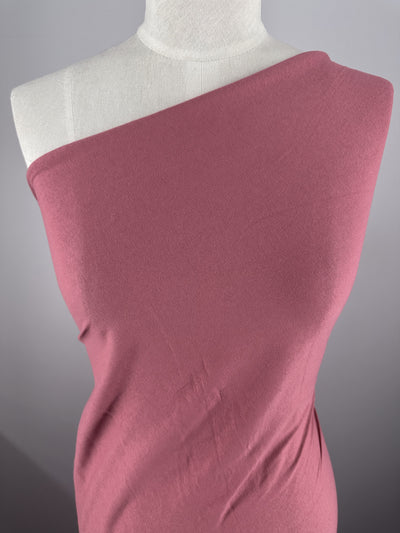 A mannequin draped in Super Cheap Fabrics' Cotton Jersey - Slate Rose - 175cm stands gracefully against a gray background.