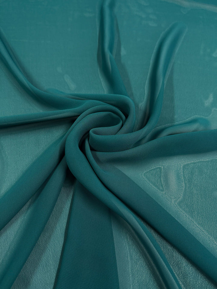Hi-Multi Chiffon - Alexandrite by Super Cheap Fabrics is a teal polyester sheer fabric, 150cm wide, featuring a swirling circular pattern that highlights its semi-transparent, soft, and flowing texture.