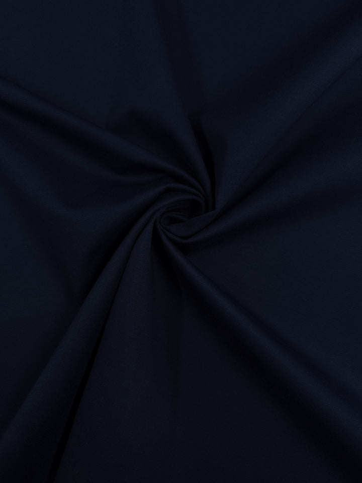 A close-up of Super Cheap Fabrics' Milano Ponte - Mood Indigo (160cm), highlighting the soft folds, smooth texture, and flexible 4-way stretch of this heavyweight dark navy blue ponte fabric.