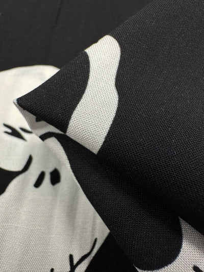 Close-up of "Skellington" by Super Cheap Fabrics, a versatile printed rayon featuring black and white abstract shapes. Its textures and folds offer depth and contrast, creating an eye-catching 140cm wide print.