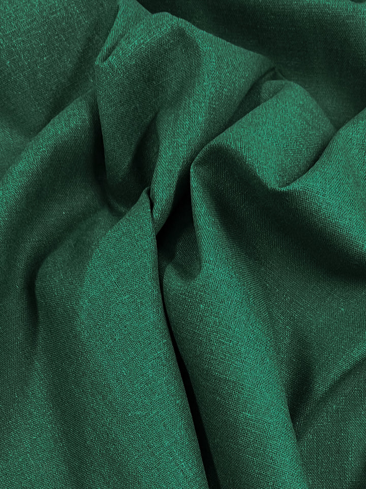 A detailed close-up of Super Cheap Fabrics' Premium Linen Cotton in the vibrant Aventurine shade, showcasing its smooth texture with graceful folds and subtle shadows. This lightweight material appears soft and has a slight sheen that reflects the light, enhancing its captivating hue. Measuring 140cm in width, this fabric combines style and quality.