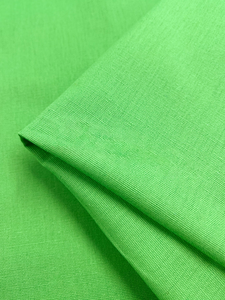 A neatly folded piece of Super Cheap Fabrics' Linen Blend in Summer Green, 150cm wide, with a smooth texture and medium weight displayed against a plain background.