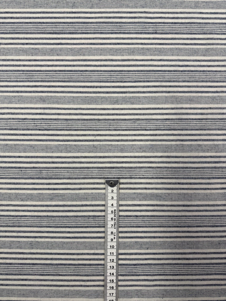 The Super Cheap Fabrics Linen Blend - Coastal Navy Stripe (140cm) features lightweight fabric with horizontal navy and white stripes of varying thickness; a measuring tape alongside shows about 17 inches for scale.