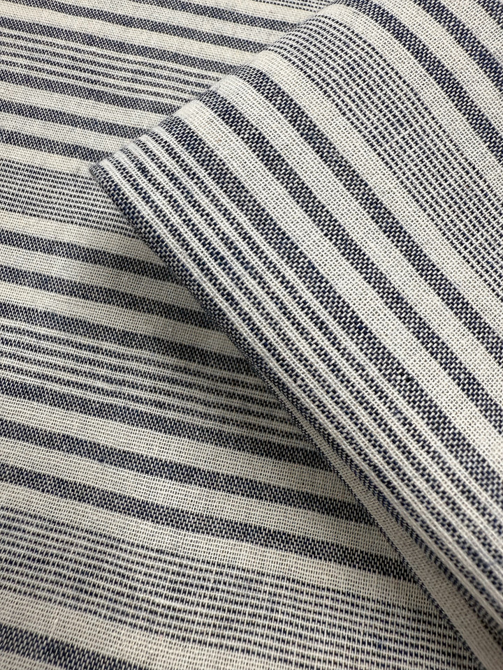 Close-up of two layered pieces of Super Cheap Fabrics' Linen Blend - Coastal Navy Stripe (140cm), showcasing a woven texture with horizontal navy and white stripes in varying thicknesses.