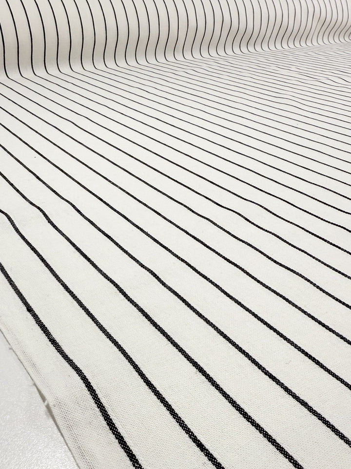 A close-up of Super Cheap Fabrics' Linen Blend - Classic Chalk Pinstripe (135cm) shows black and white fabric with thin, evenly spaced black vertical stripes for a clean and simple linear pattern.