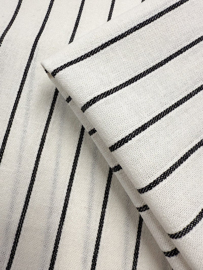 Close-up of two overlapping pieces of Super Cheap Fabrics' Linen Blend - Classic Chalk Pinstripe (135cm), featuring black and white fabric with evenly spaced, thin black diagonal stripes.