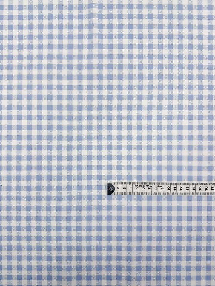 Super Cheap Fabrics’ Linen Blend - Powder Blue Picnic (140cm) features a light blue and white gingham on soft linen, ideal for summer jackets. A measuring tape at the bottom right illustrates the fabric's scale.