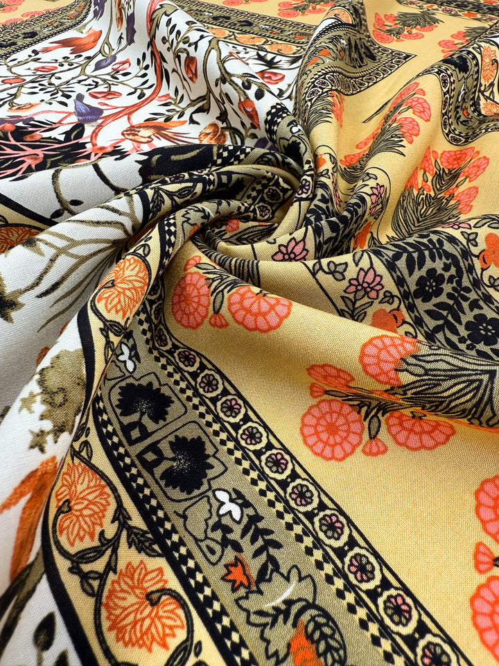 Close-up of Super Cheap Fabrics’ Designer Rayon - Antique Tapestry (145cm), showcasing intricate floral and geometric patterns in black, orange, yellow, and cream, with the material softly gathered and folded.