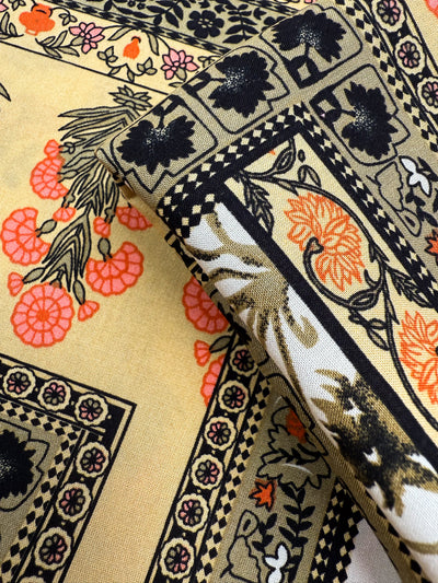 A close-up of Designer Rayon - Antique Tapestry by Super Cheap Fabrics shows folded, vibrant rayon with floral and geometric patterns in black, orange, and pink on beige, featuring flowers, leaves, and decorative borders. Width: 145cm.