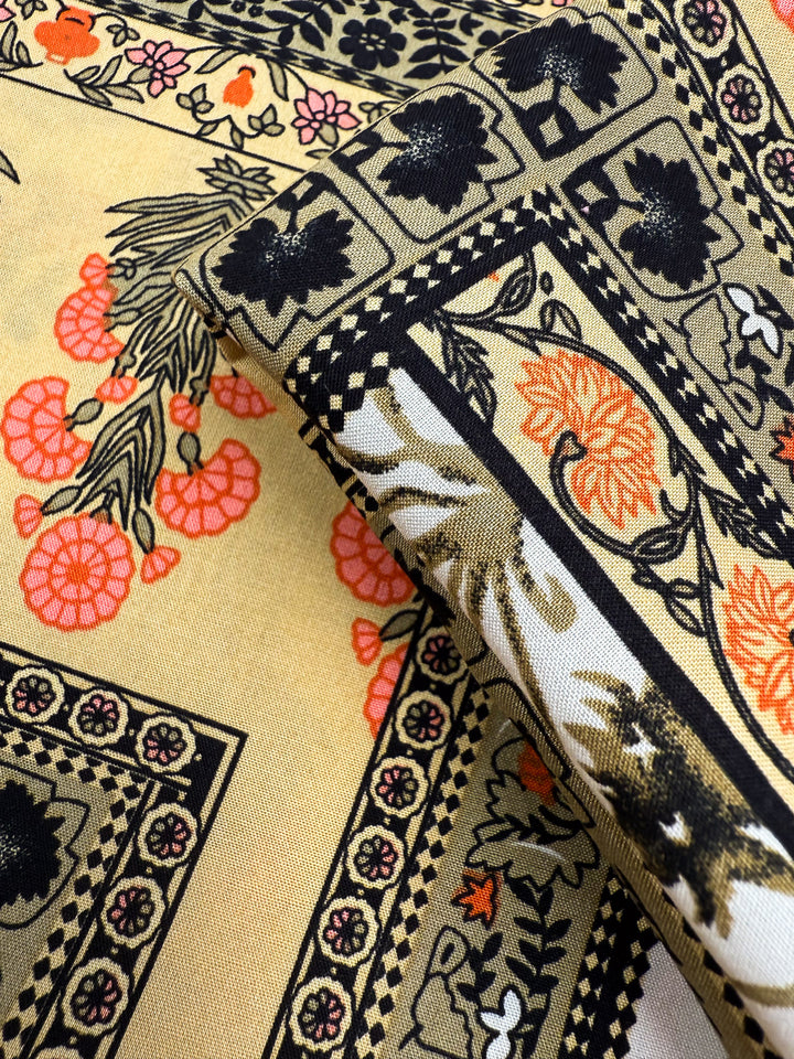 A close-up of Designer Rayon - Antique Tapestry by Super Cheap Fabrics shows folded, vibrant rayon with floral and geometric patterns in black, orange, and pink on beige, featuring flowers, leaves, and decorative borders. Width: 145cm.