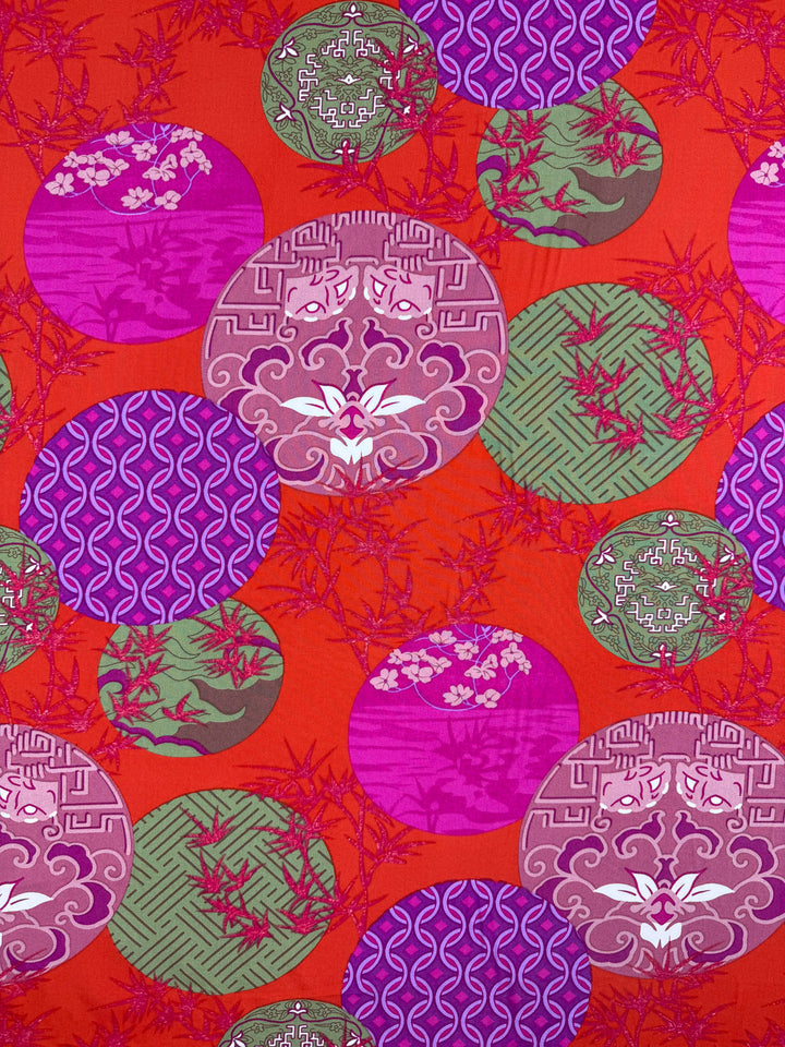 Super Cheap Fabrics' Designer Rayon - Kyoto Lanterns (146cm) features bold pink, purple, and green geometric and floral circles overlapping on a bright red background with bamboo accents.