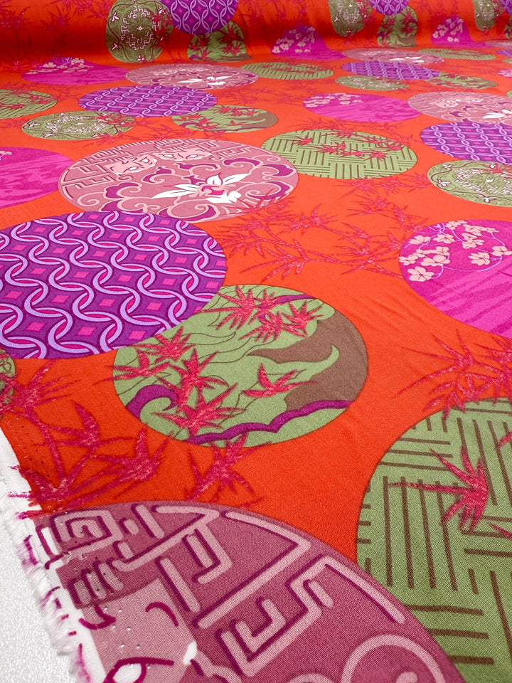 Super Cheap Fabrics' Designer Rayon - Kyoto Lanterns (146cm) features a red background with colorful pink, purple, and green circles in geometric and floral patterns, including leaves, waves, and intricate line details.