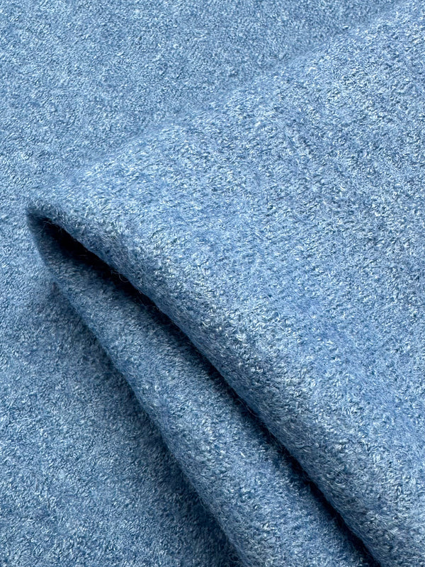 A close-up of folded light blue Boiled Wool - Allure from Super Cheap Fabrics shows its soft, fuzzy surface. The thick wool-viscose blend appears cozy and warm in its gentle hue, offering a sense of comfort.