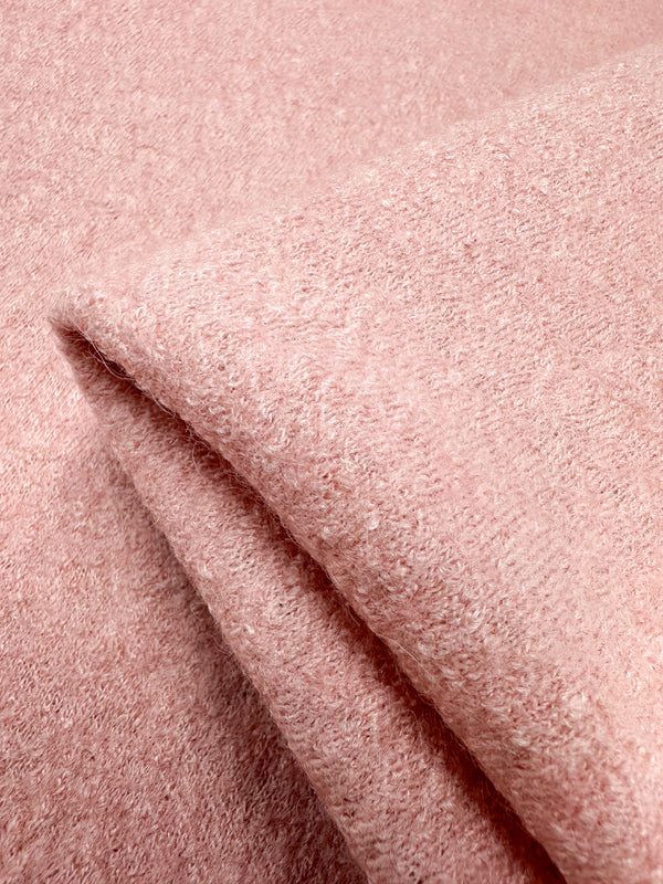 A close-up shows a folded piece of Boiled Wool from Super Cheap Fabrics in powder pink. The 145cm wool-viscose blend appears soft, textured, plush, cozy, with a subtle sheen.