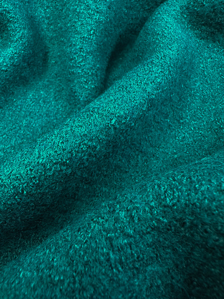 Close-up of "Boiled Wool - Everglade - 135cm" by Super Cheap Fabrics, a teal wool-viscose blend with a soft, textured surface featuring a slightly fuzzy look and subtle depth with gentle folds and shadows.