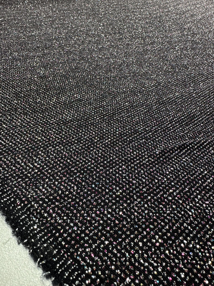 This 150cm Metallic Lycra - Disco from Super Cheap Fabrics features a shimmering black base with silver and purple metallic threads. Ideal for dazzling dresses, this medium-weight fabric has a slightly rough texture and visible edges highlighting its multi-color allure.